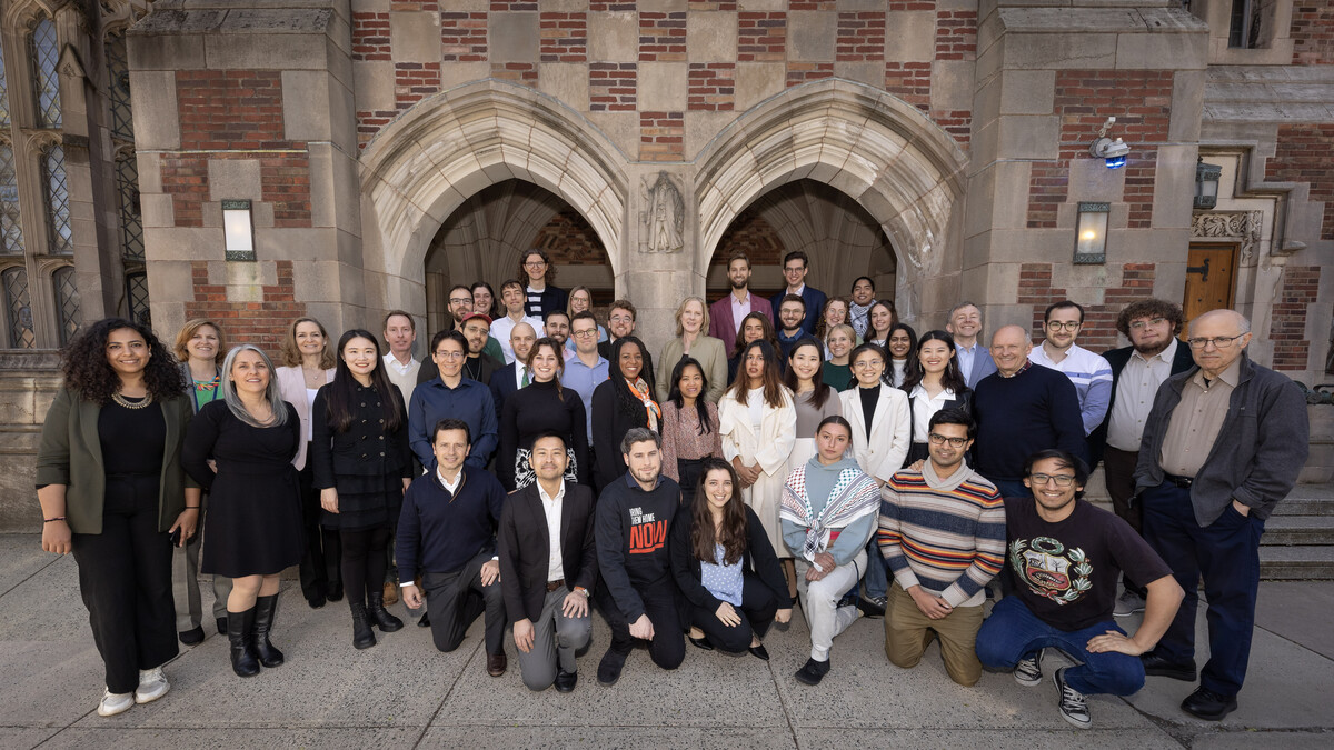 Graduate students in the class of 2024 pose in front of a pair of Gothic stone arches
