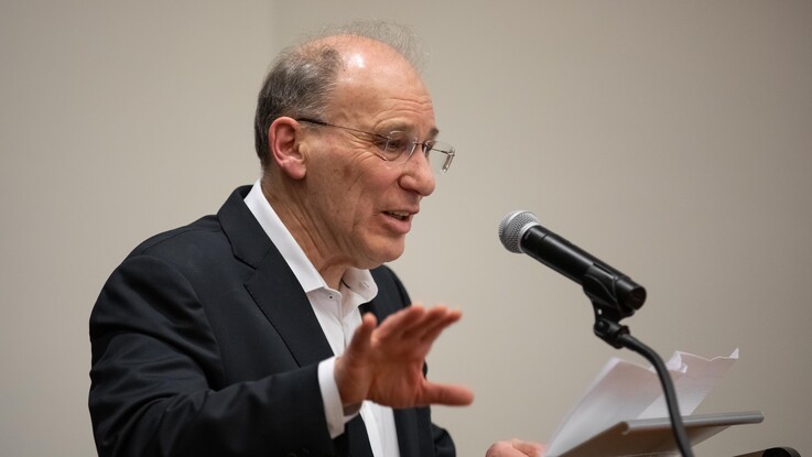 David Strauss speaks into a microphone gesturing with his hand