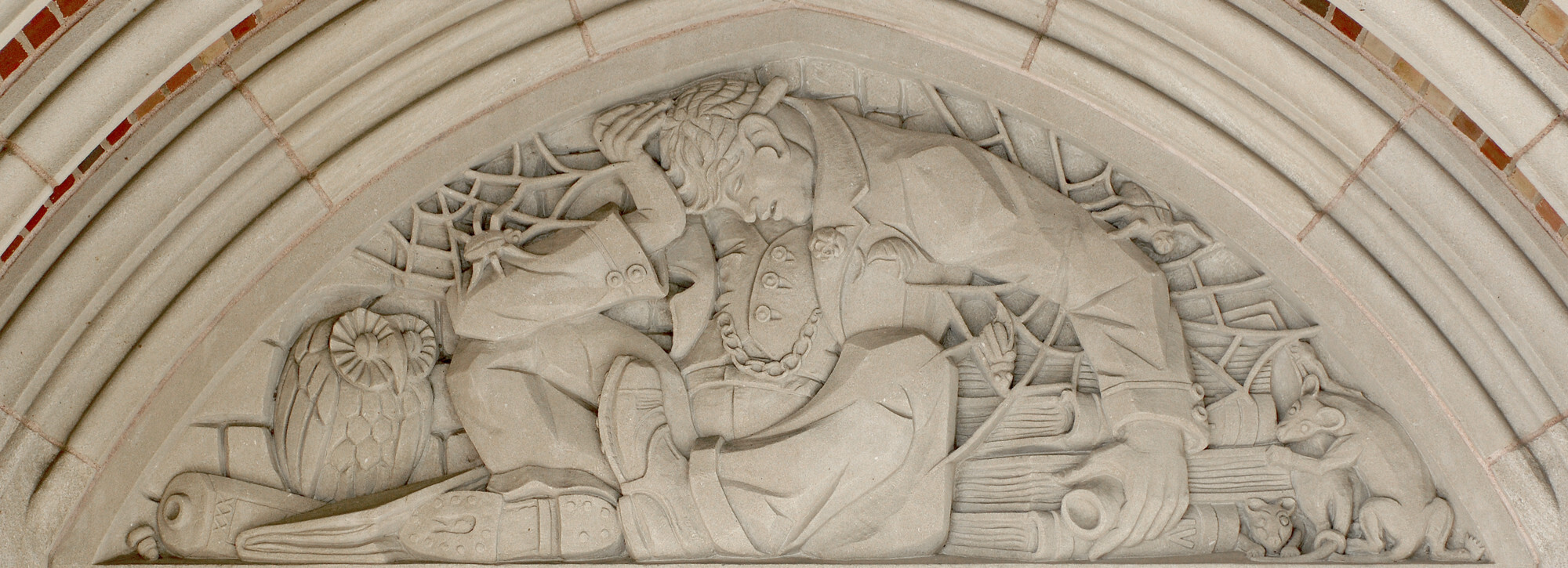 A stone scene of a sleeping student with his head in his hand in an archway.